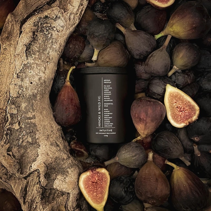 A FableRune Hinoki and Wild Fig candle surrounded by figs and natural wood